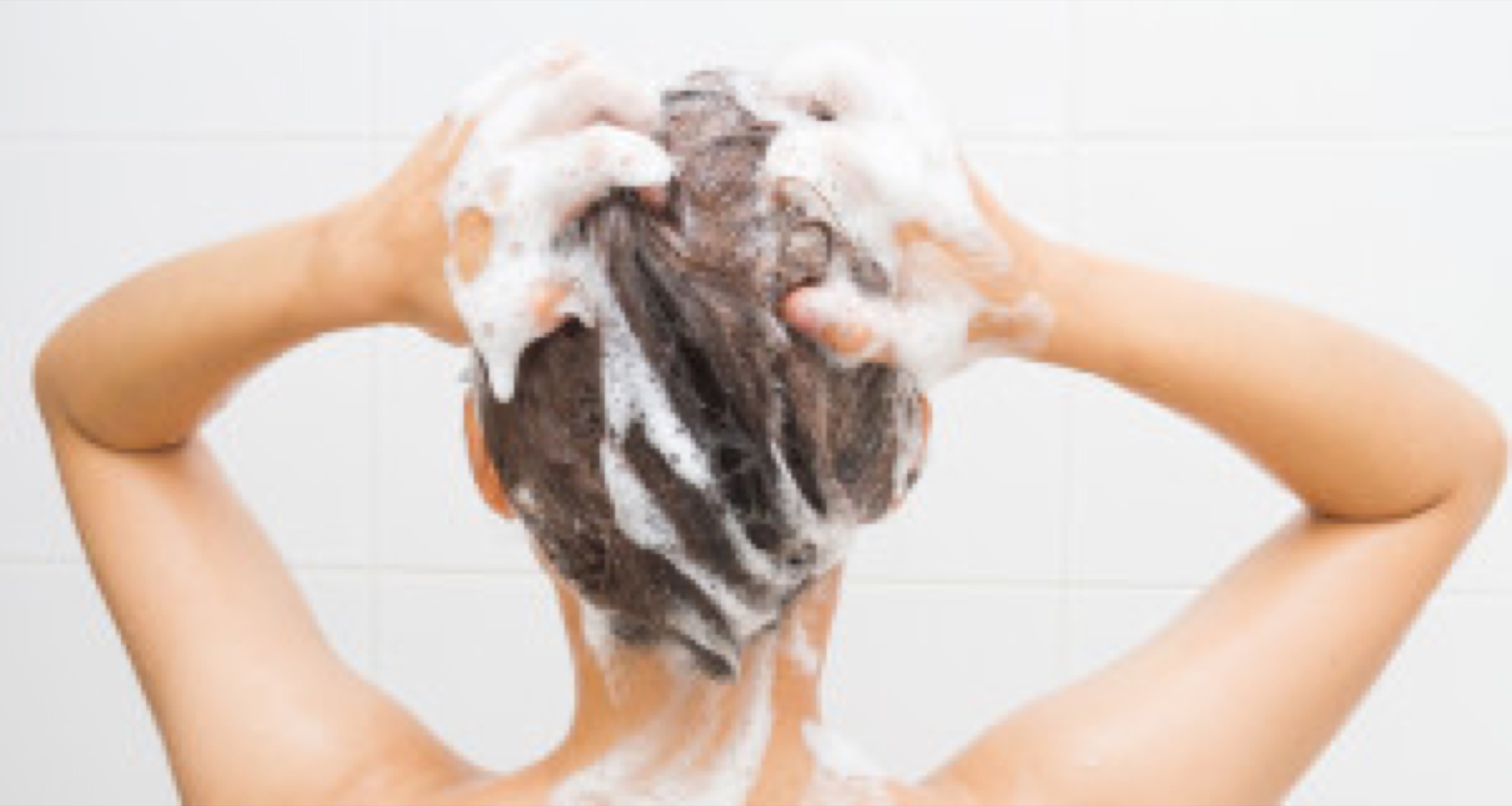Woman washing her hair on white tiles background.