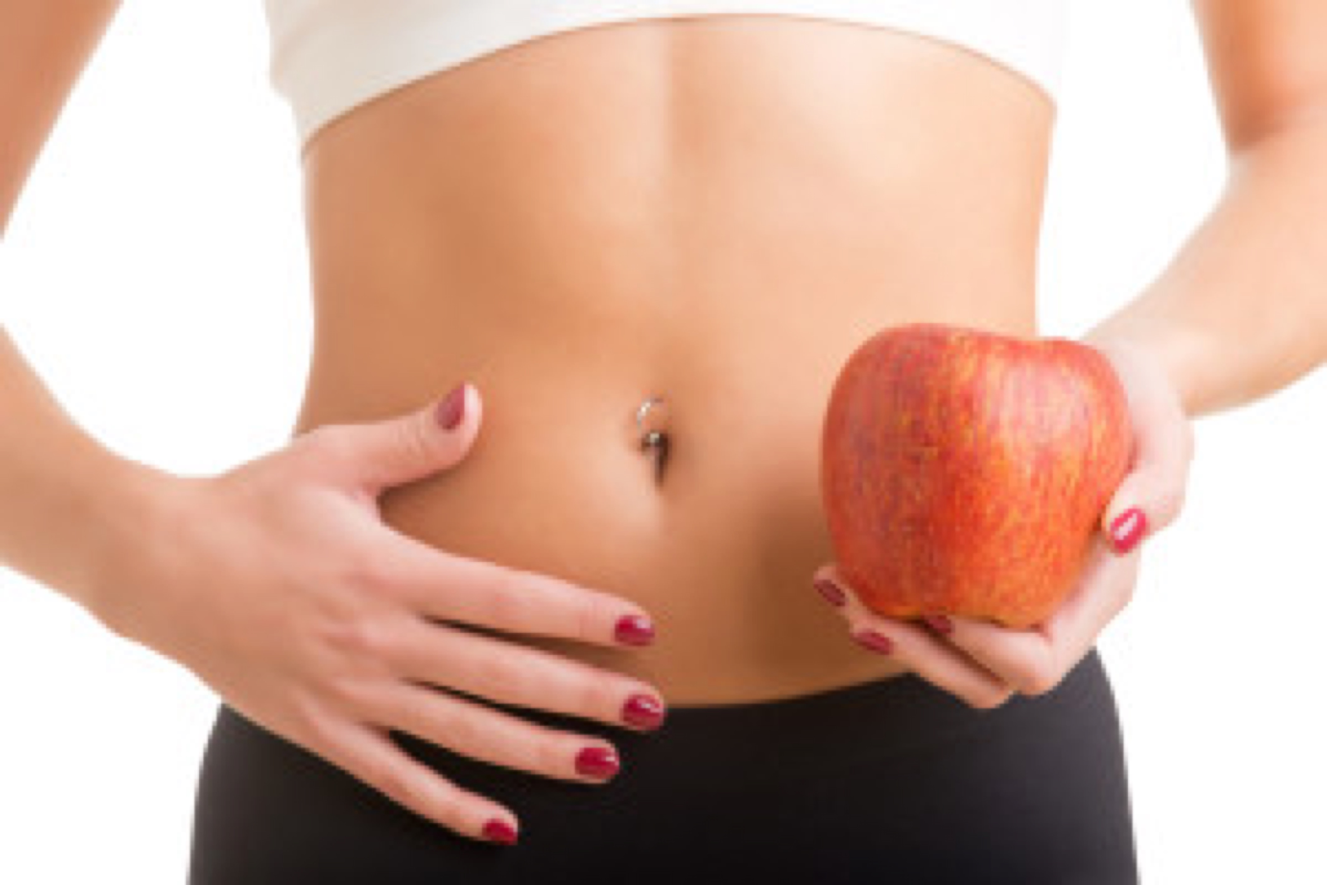Woman holding an apple with a hand on her abdomen. Focus on the apple.