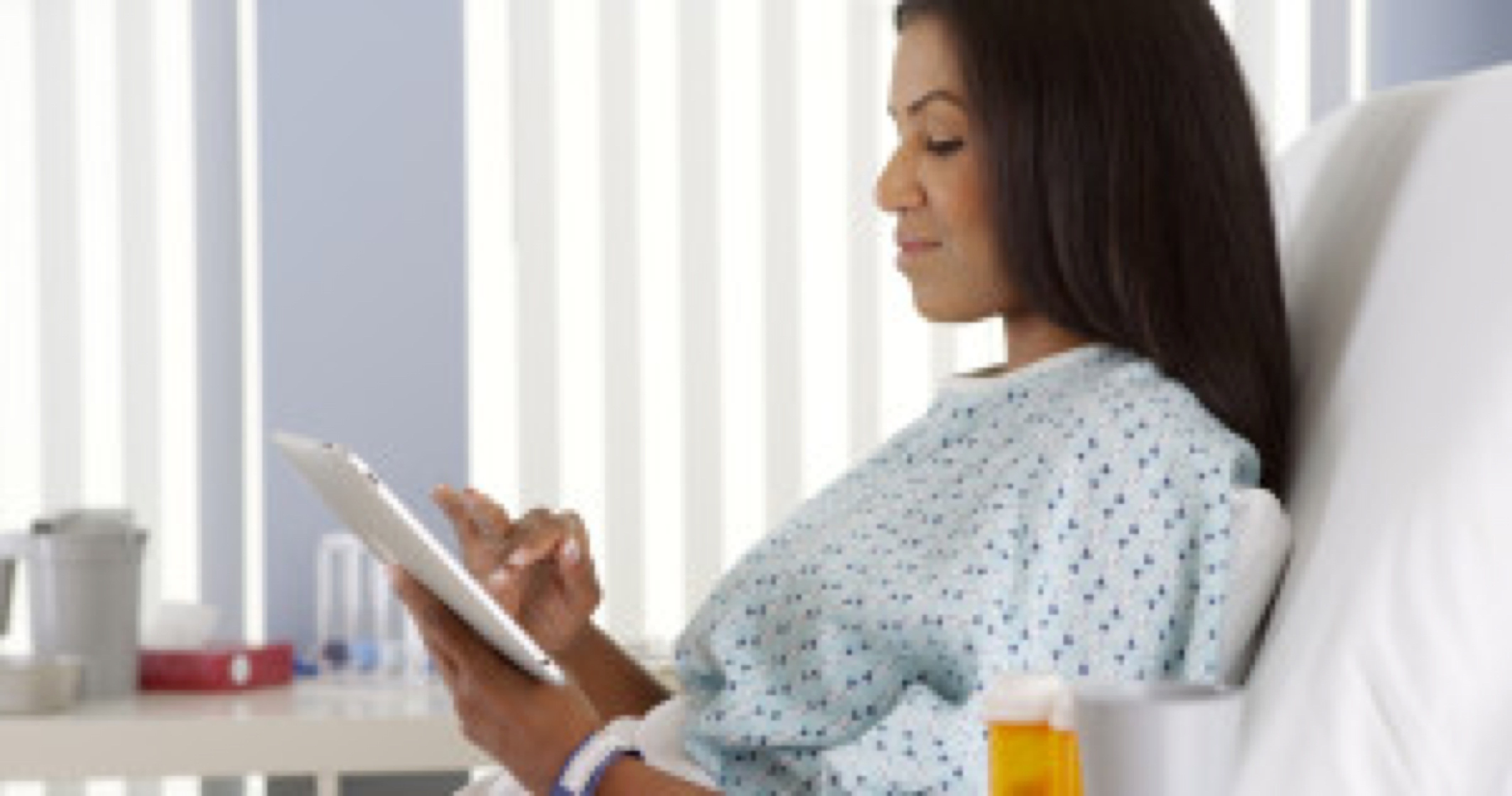African American woman using tablet computer in hospital bed