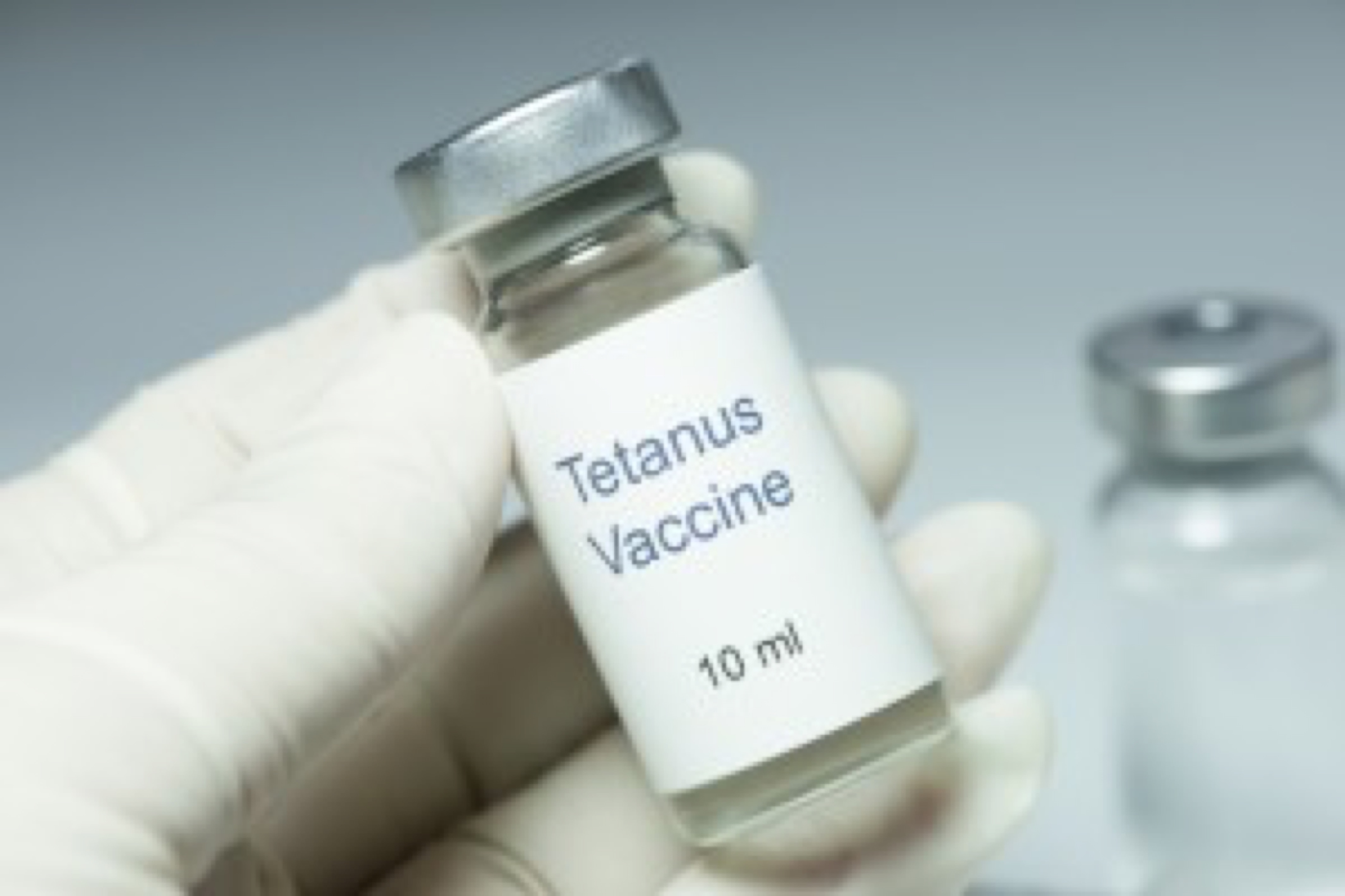 Tetanus vaccine in glass vial with gloved hand.  All labels, paperwork, etc. are fictitious, and numbers/letters/serials are random.