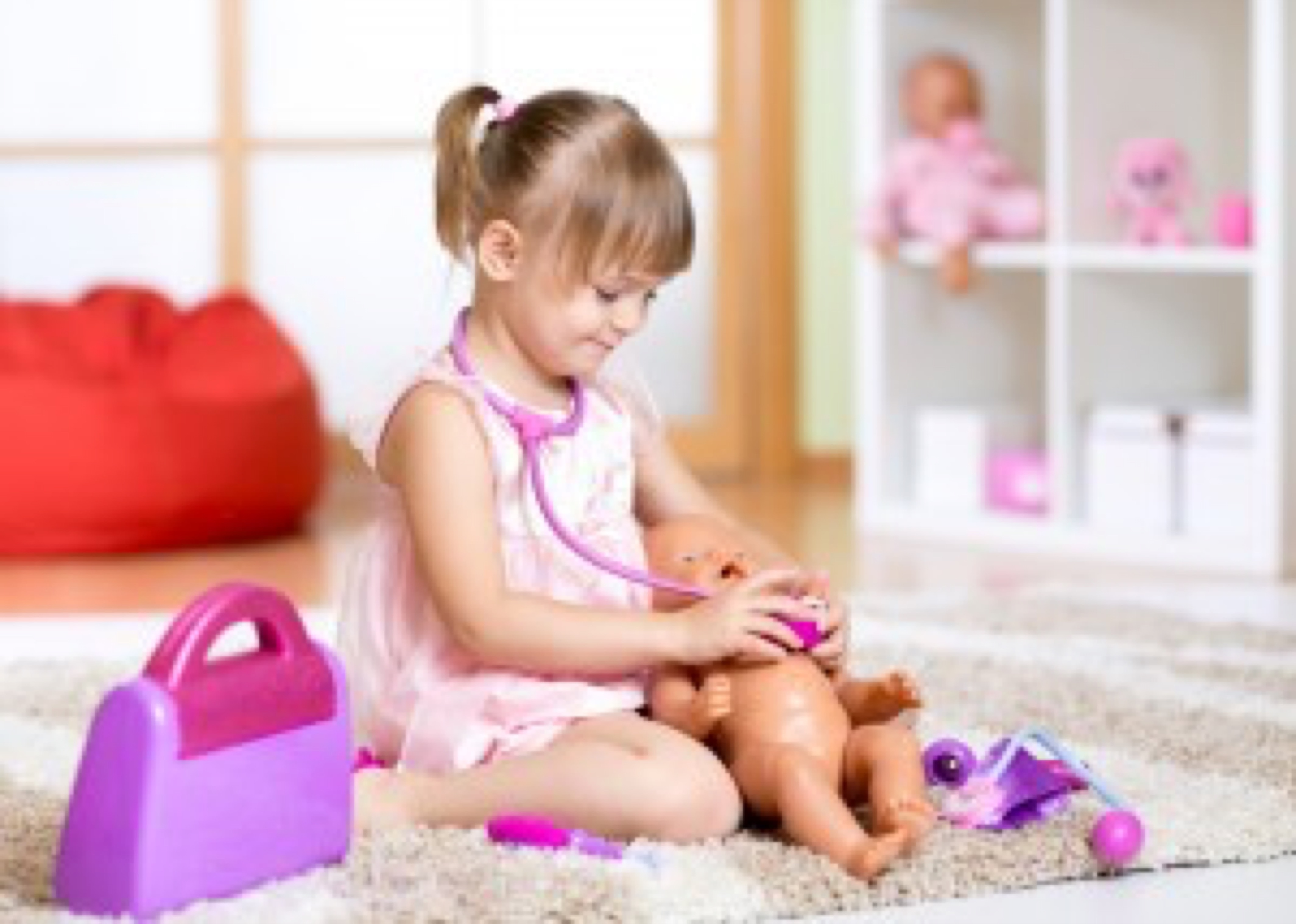 child girl playing doctor with toy at home