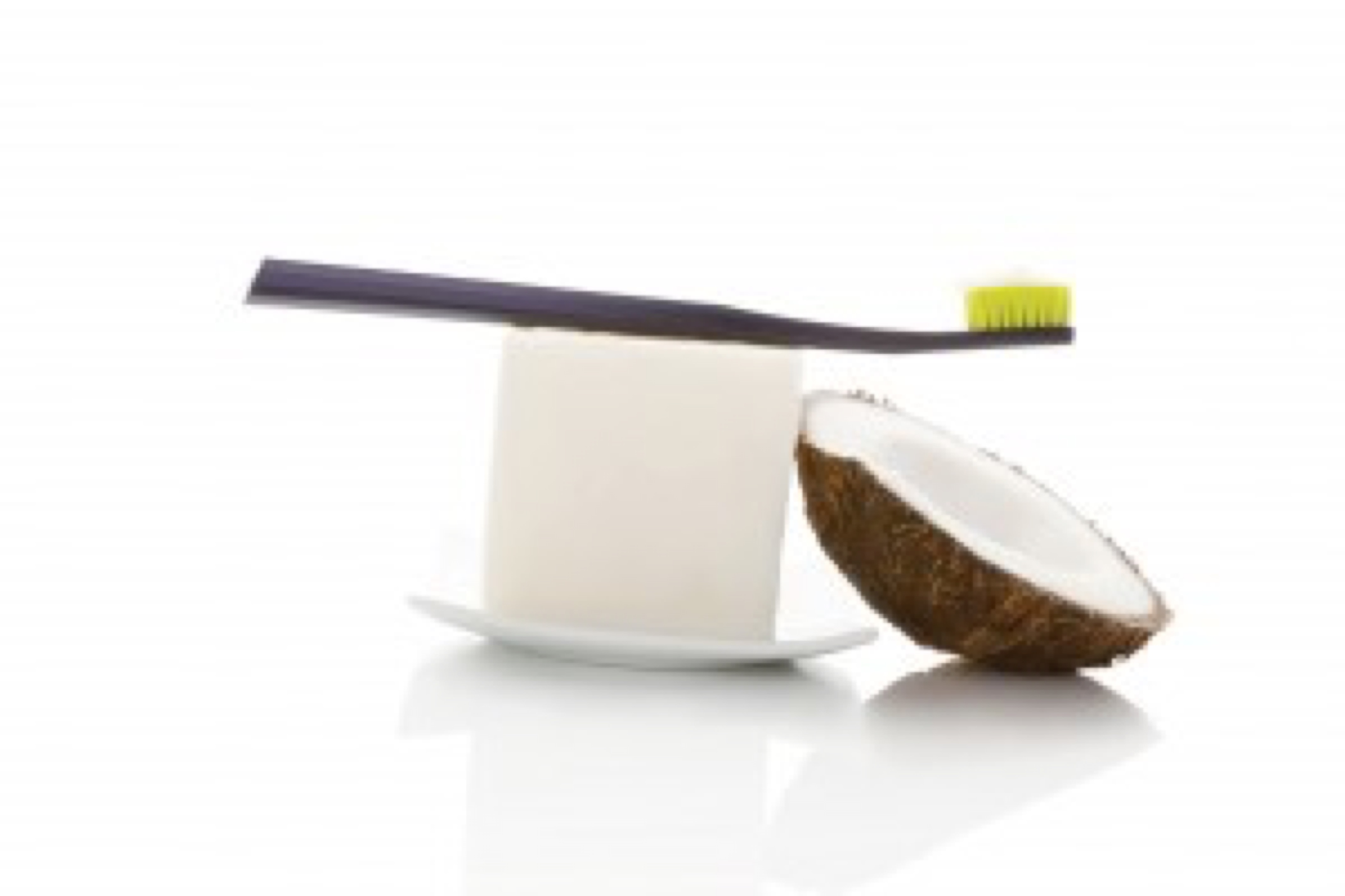 Hard organic coconut oil with toothbrush and coconut isolated on white background. Natural organic dental hygiene.