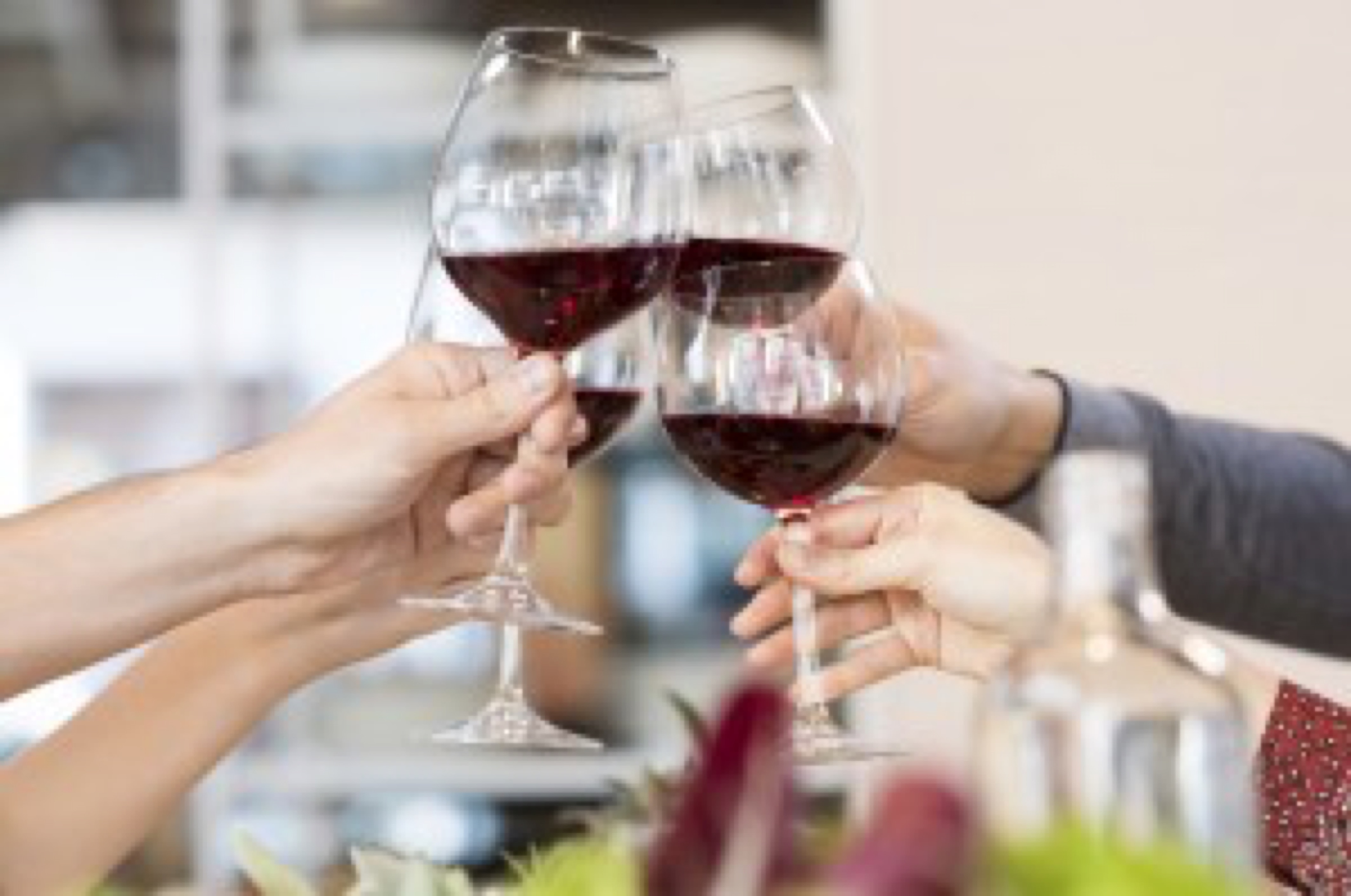 Close up of glasses raising a toast at lunch. Closeup of friends toasting glasses of red wine in a party. Group of friends a toast to the cheers of red wine at restaurant.